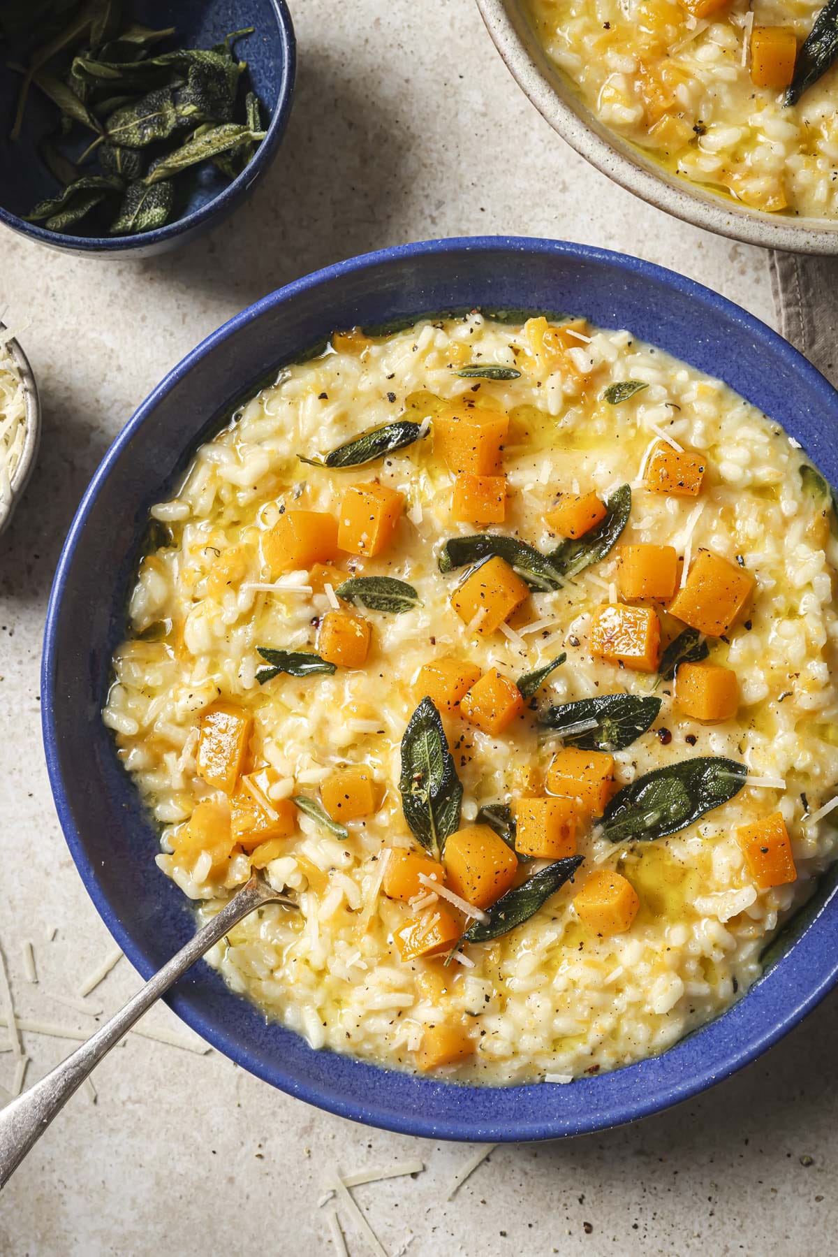 Butternut squash risotto in a blue bowl with a spoon.