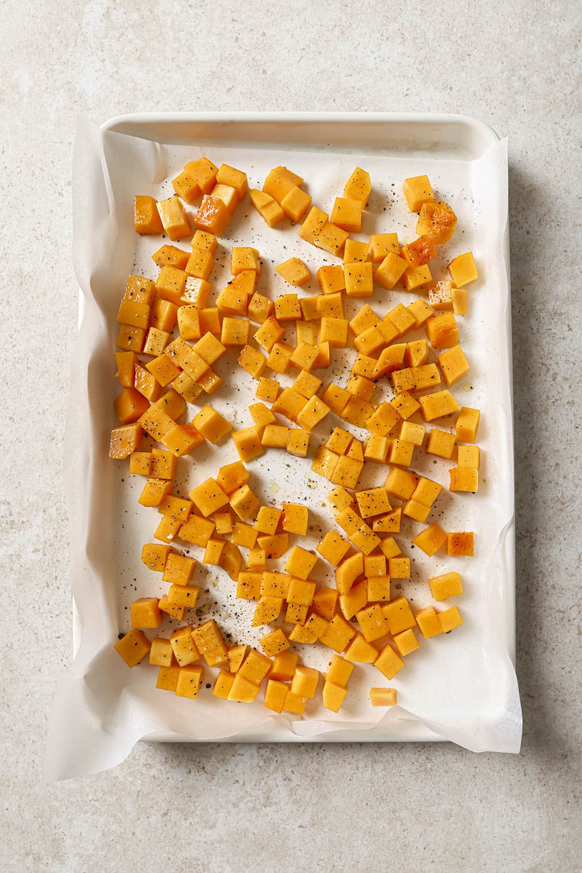 Cubed butternut squash on a baking sheet.