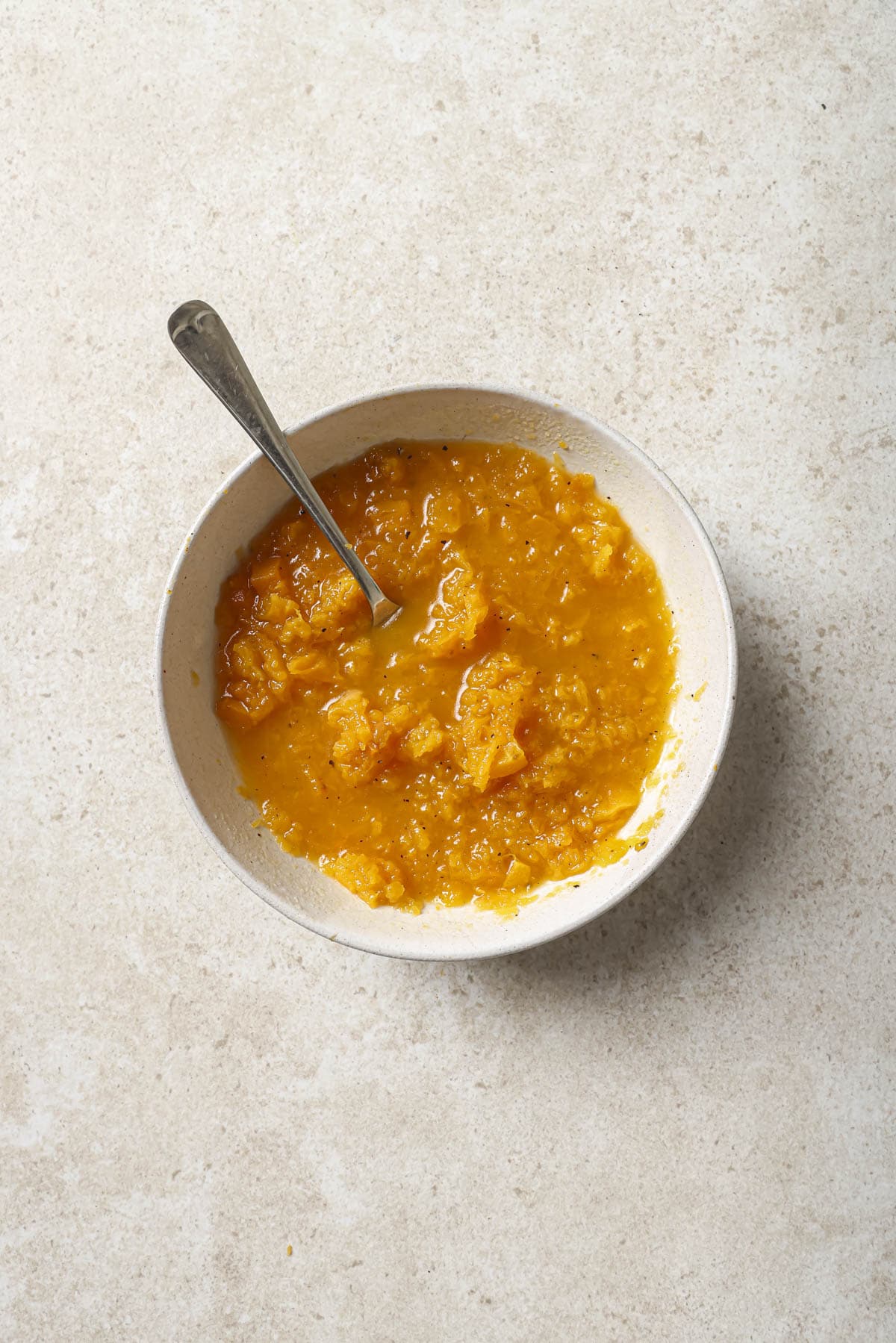 Mashing butternut squash with chicken broth.