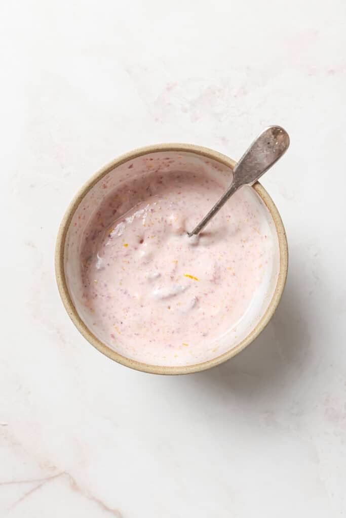 Stirring cranberry sauce with creme fraiche and orange zest in a small bowl.