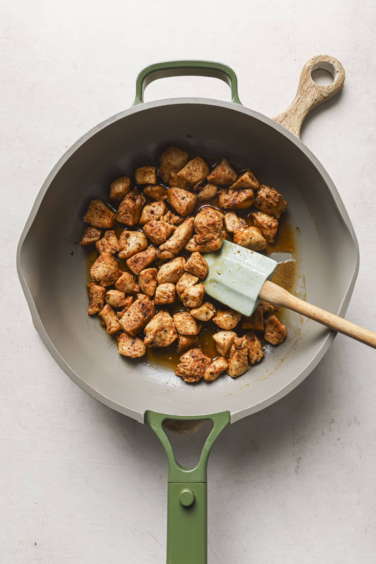 Cooking chunks of chicken in a large skillet.