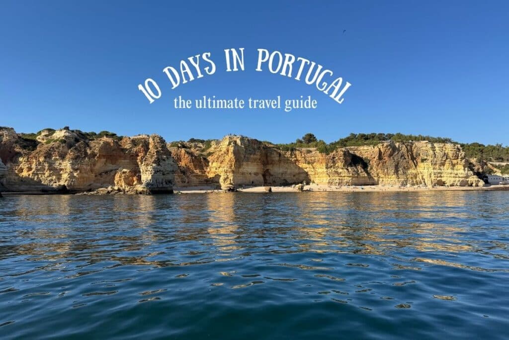 Scenic coastal cliffs in Portugal reflecting on the calm blue ocean under a clear sky, with white text overlay reading “10 Days in Portugal – the ultimate travel guide.