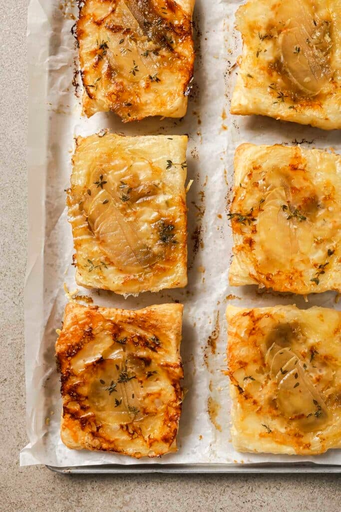 Flipped puff pastry apple tarts on a baking sheet pan.
