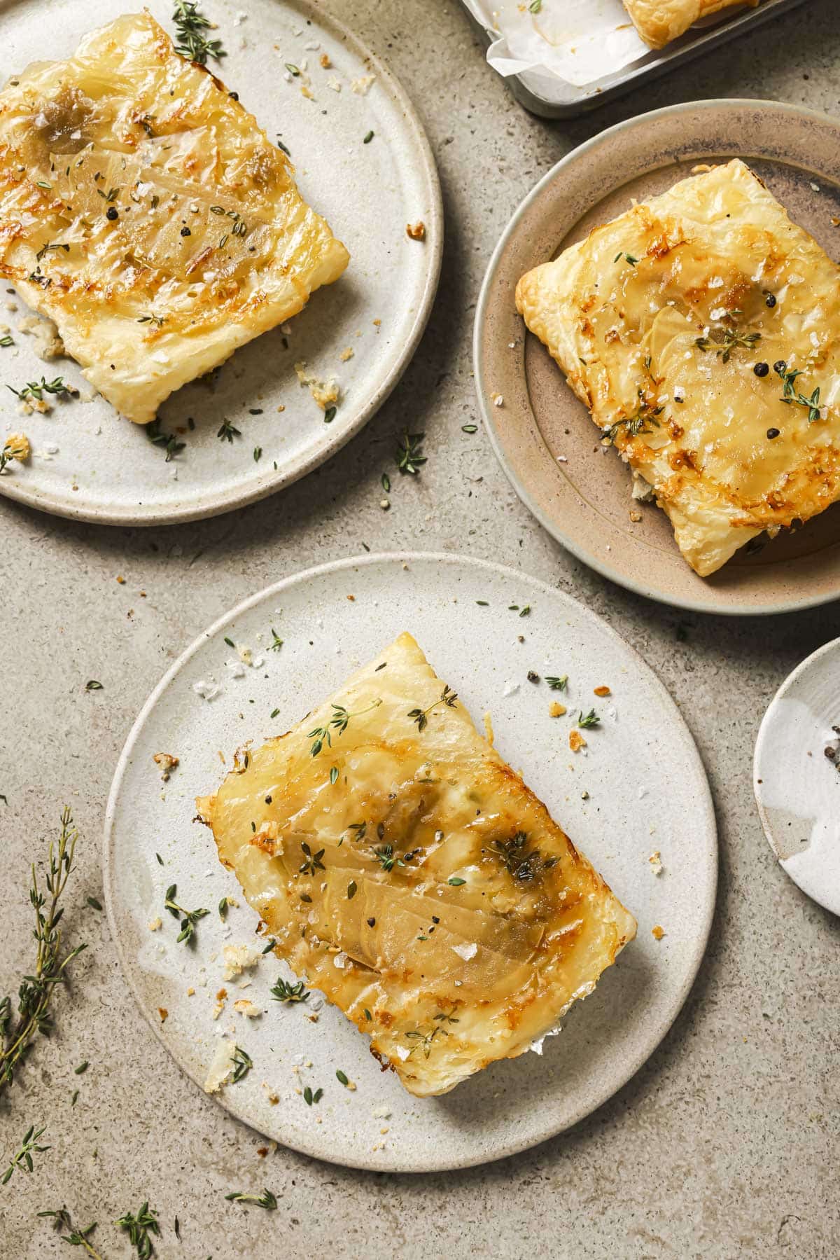 Puff pastry apple tart on a plate garnished with fresh thyme.