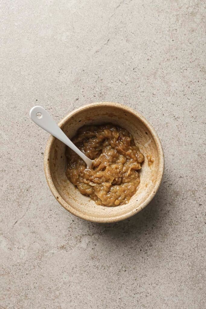 Stirring onion jam with balsamic in a small bowl.