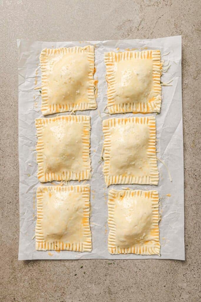 Puff pastry rectangles with crimped edges on parchment paper.