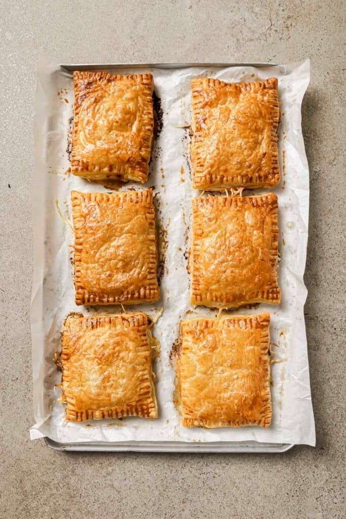 Baked puff pastry tarts on a baking sheet lined with parchment.