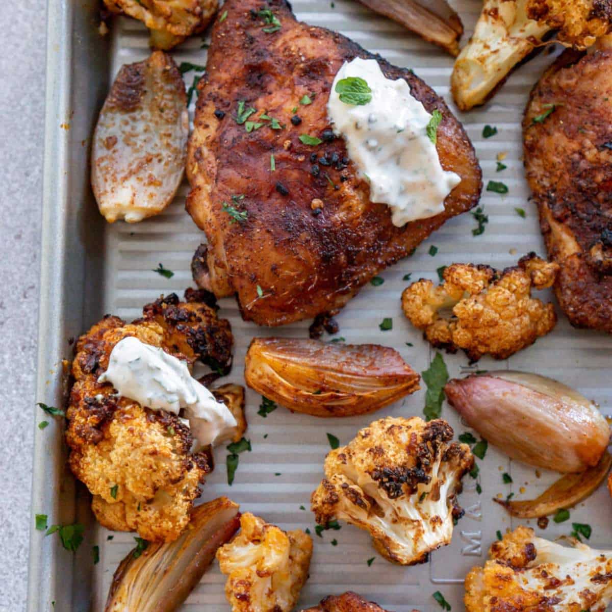 Chicken thighs and cauliflower roasted on a sheet pan.