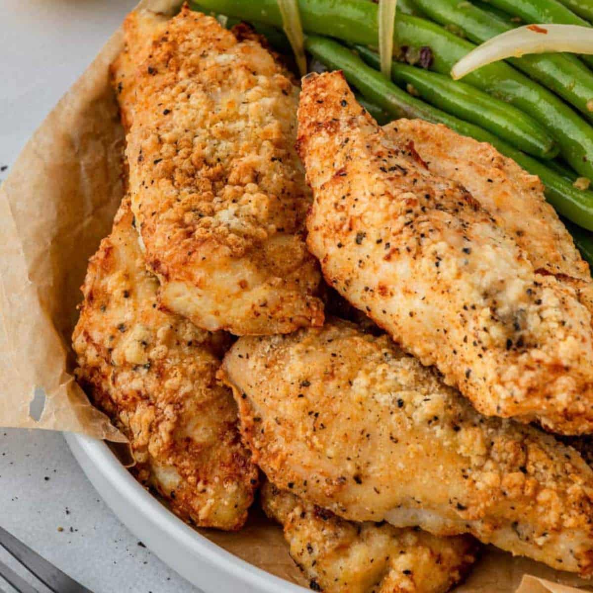 Flourless fried chicken on a plate with green beans.