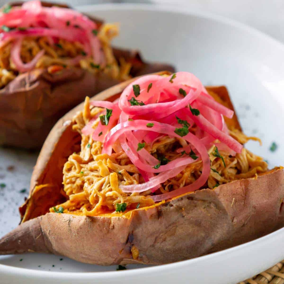 Bbq chicken stuffed sweet potato on a white plate.