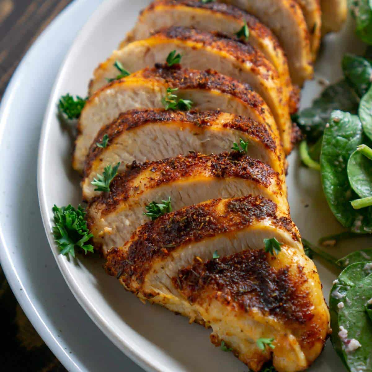 Air fryer chicken breast sliced on a plate with a salad.