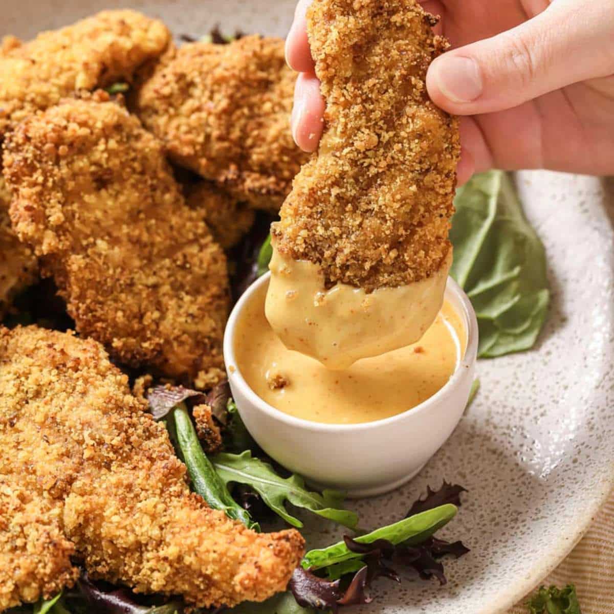 Dipping a chicken tender into sauce.