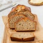 A half-loaf of banana bread with several individual slices leaned against it.