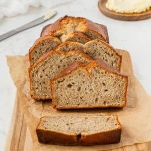 A half-loaf of banana bread with several individual slices leaned against it.