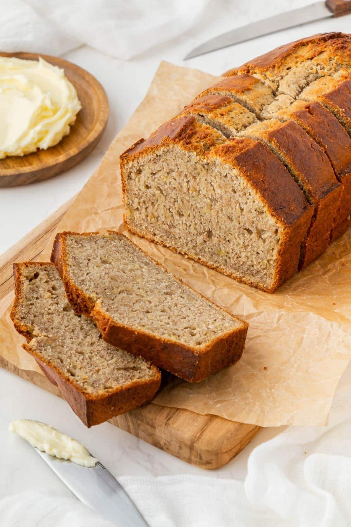 Air fryer banana bread sliced on a cutting board with butter on the side.