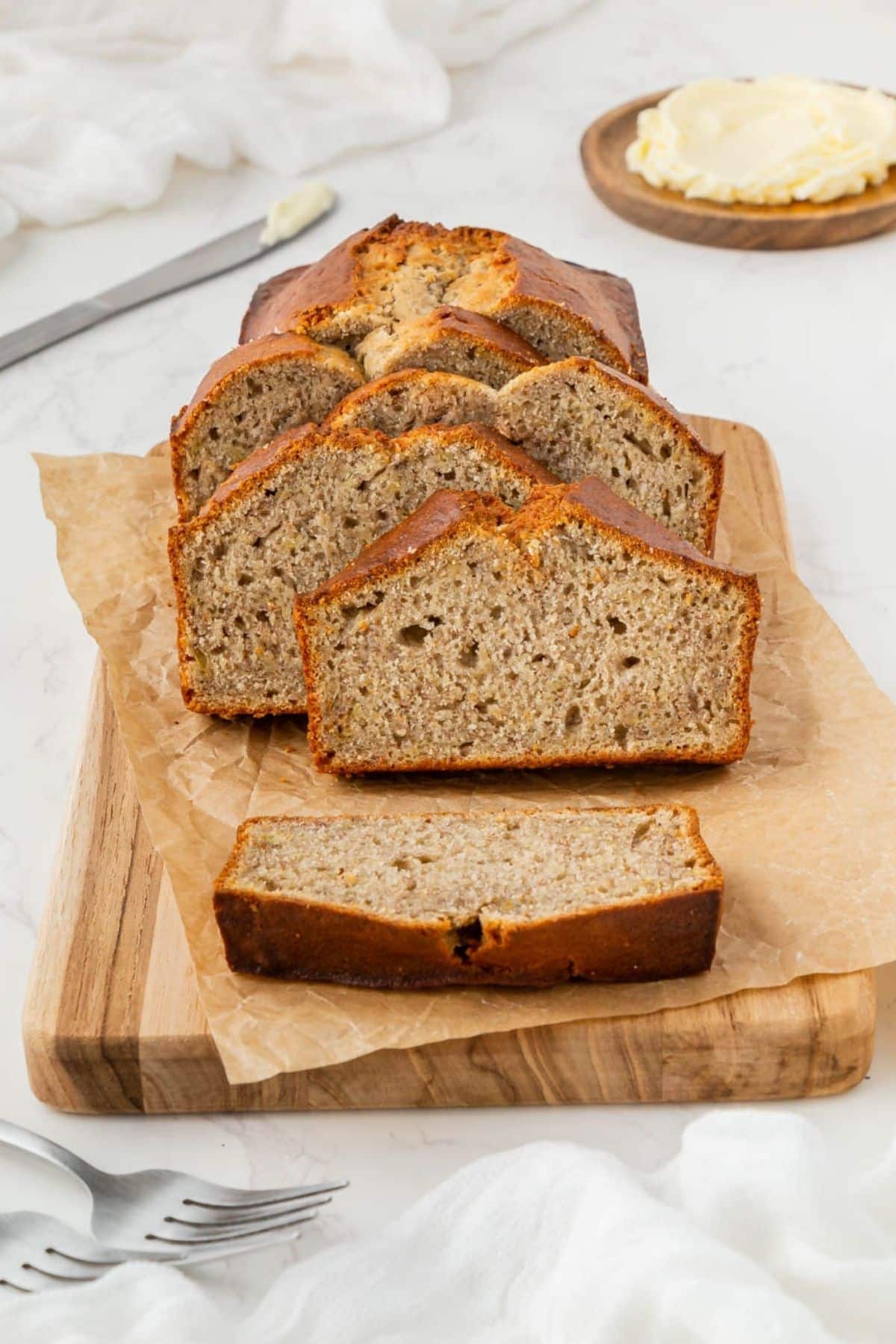 Air fried banana bread sliced on on a cutting board with parchment paper.