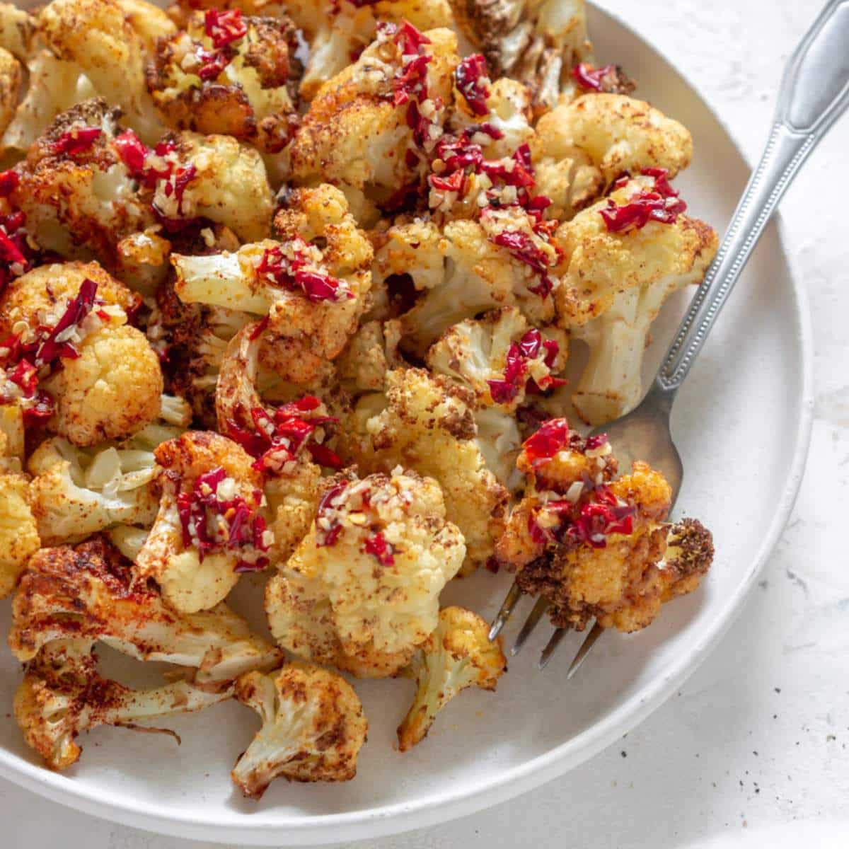 Air fryer cauliflower on a white plate with a fork.