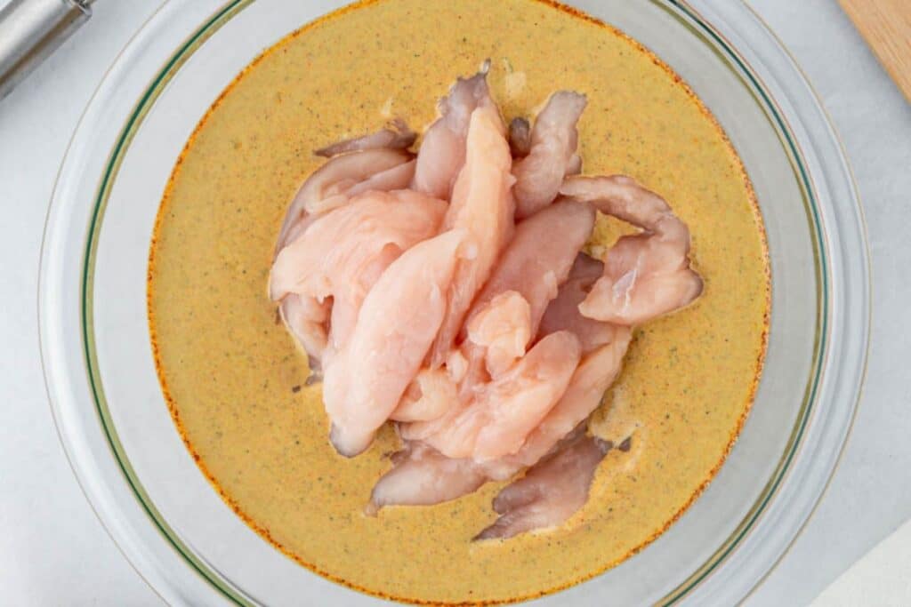 Coating chicken in shawarma marinade.