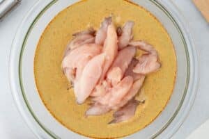 Coating chicken in shawarma marinade.