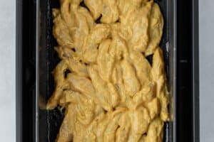 Marinated chicken in the air fryer basket.