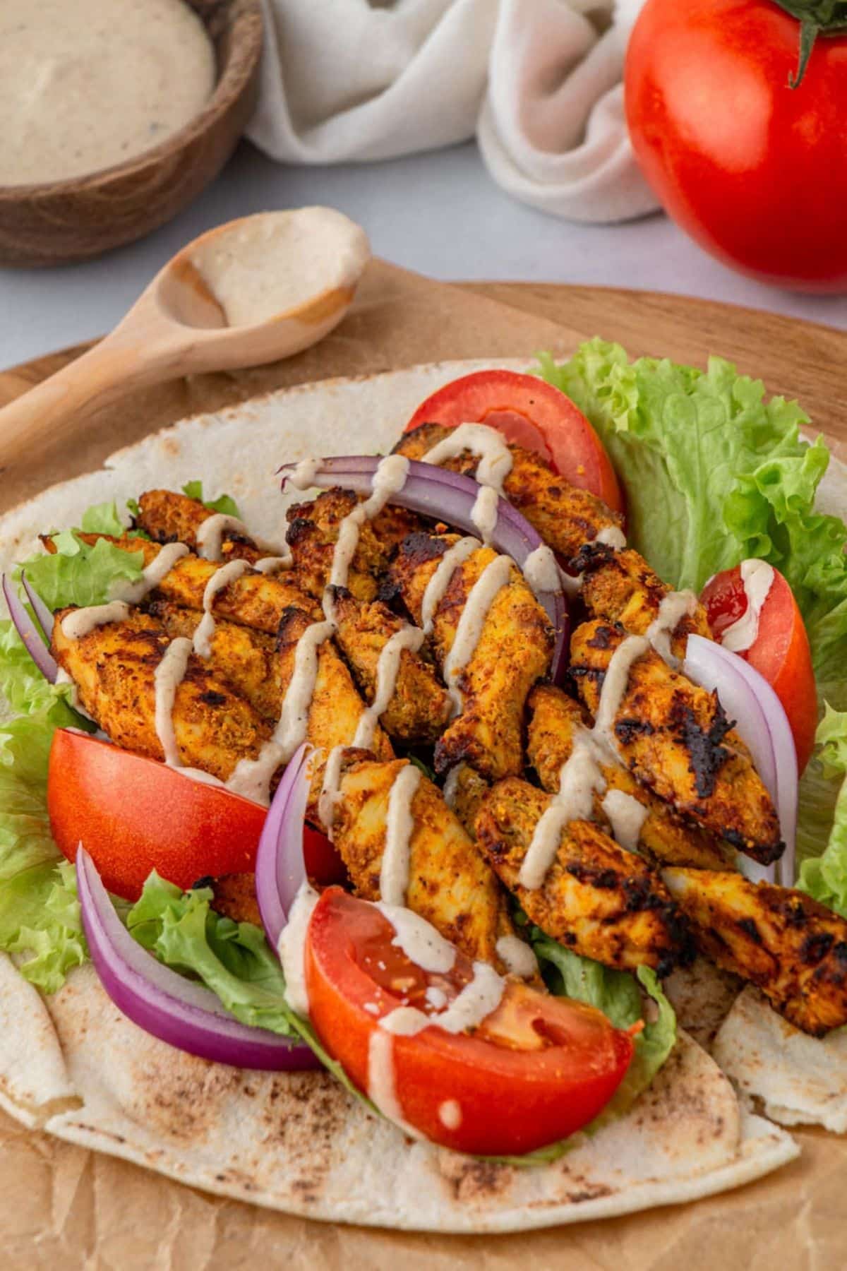Air fryer chicken shawarma on a piece of pita bread with tahini sauce.
