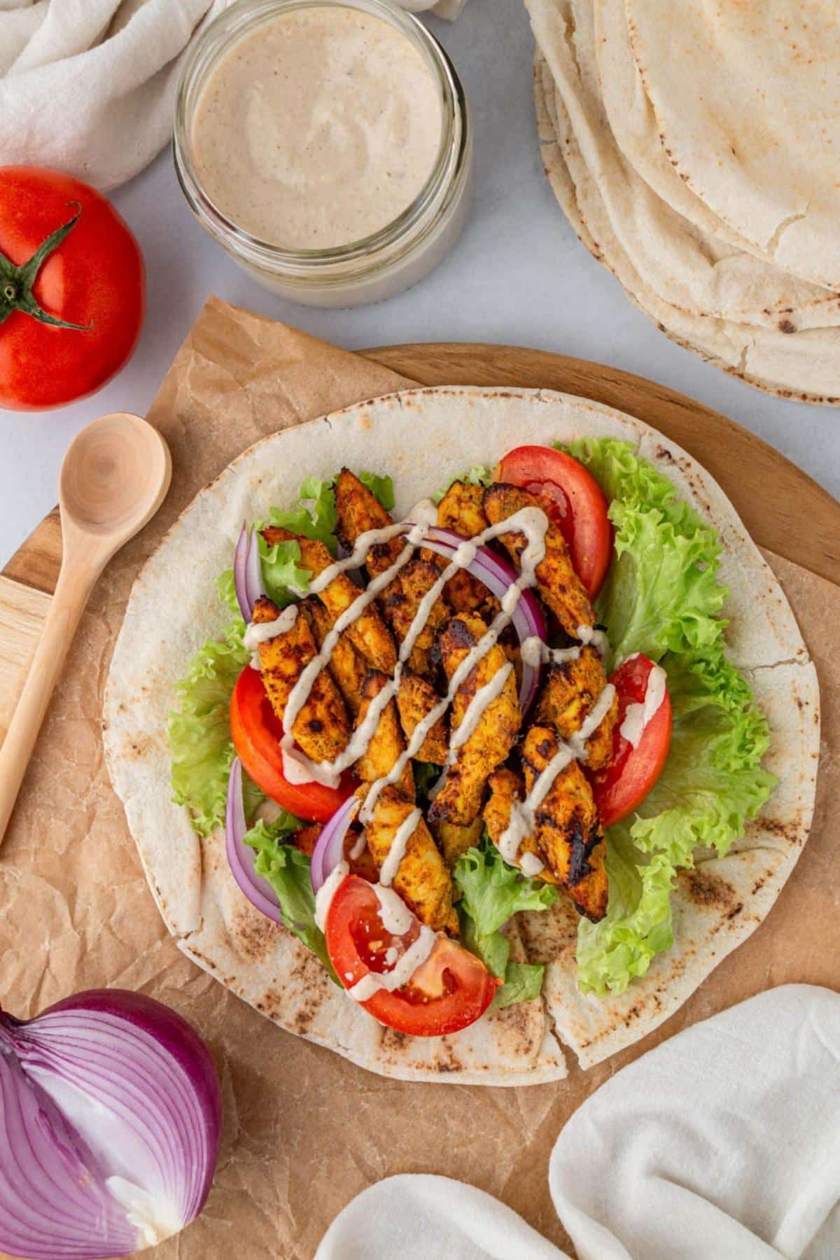 Air fried chicken shawarma with tahini sauce on a piece of pita bread.