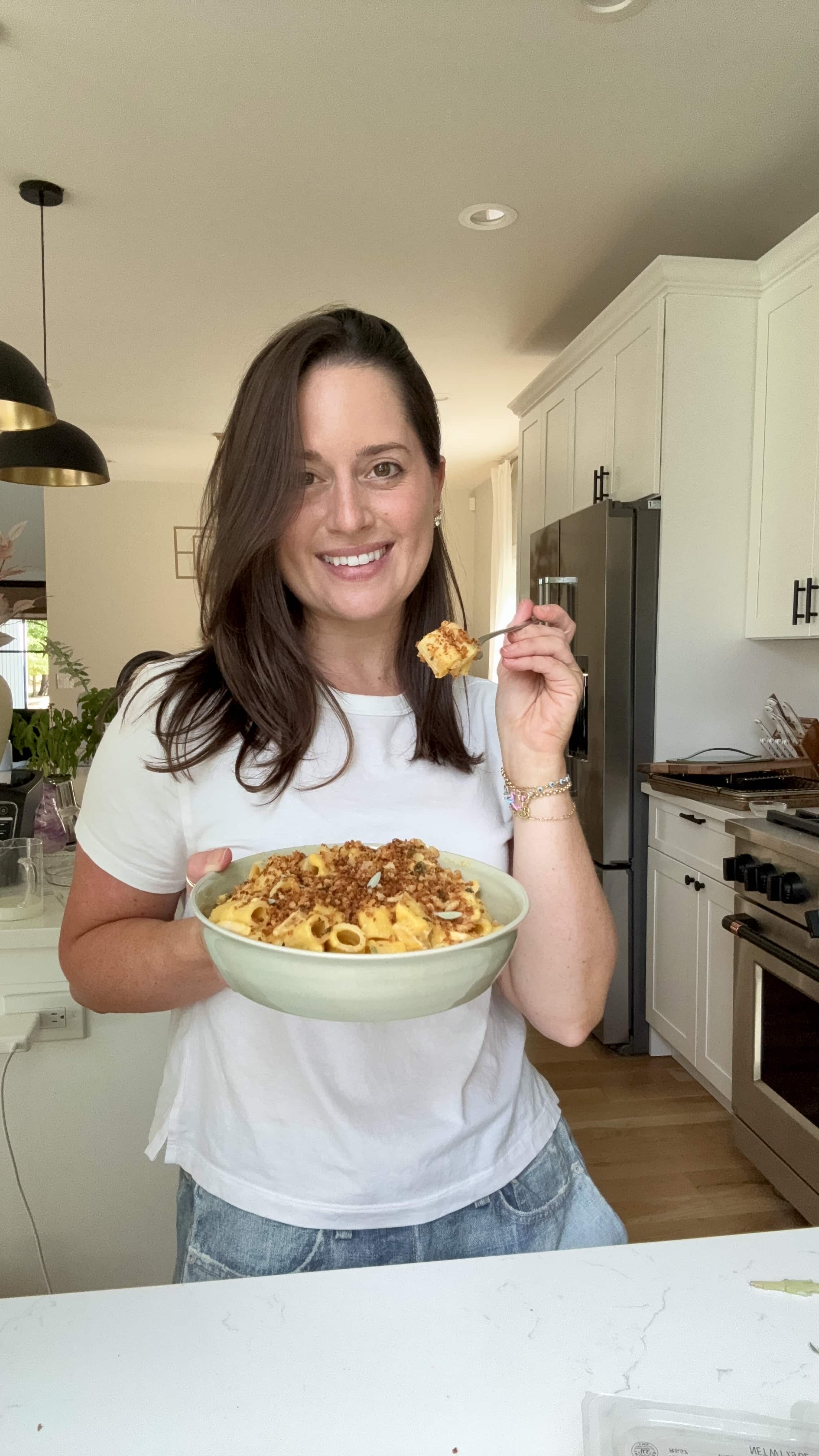 Jordan Zelesnick holding a bowl of butternut squash pasta with a bite on a fork.