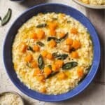 Butternut squash risotto garnished with sage in a blue bowl.