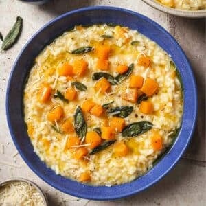 Butternut squash risotto garnished with sage in a blue bowl.