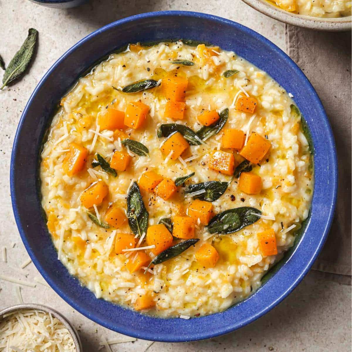 Butternut squash risotto garnished with sage in a blue bowl.