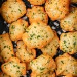 Golden, fluffy air fryer garlic knots made with crescent roll dough, sprinkled with fresh parsley and Parmesan cheese. These quick and easy homemade garlic bread knots are shown in an air fryer basket, perfectly crisp and ready to serve.