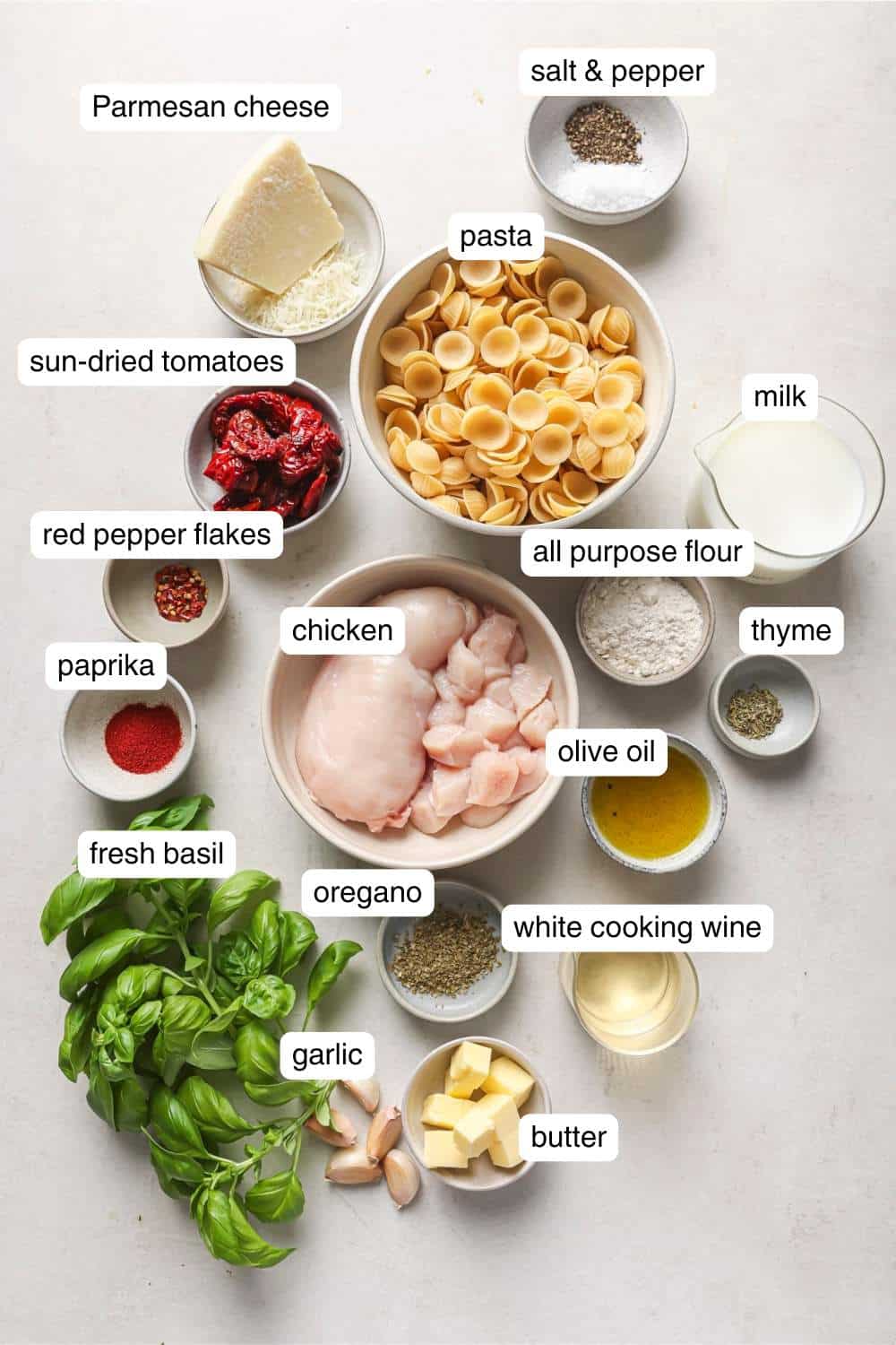 Small bowls with ingredients like spices, pasta, chicken and olive oil.