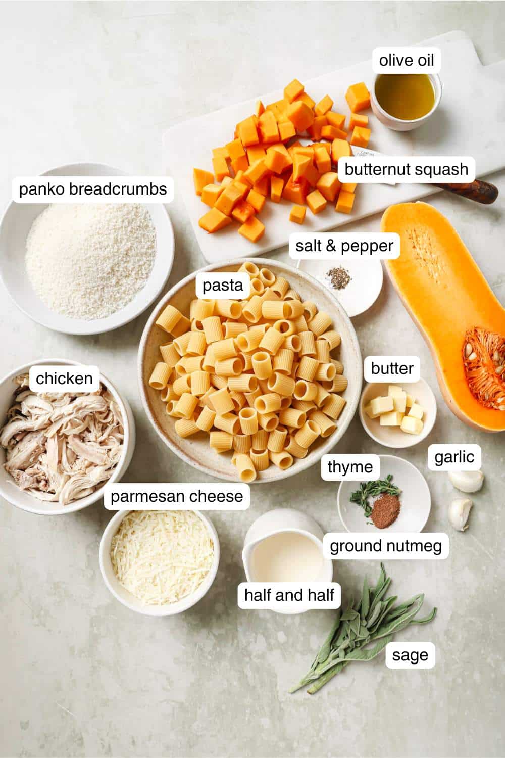 Bowls with pasta, chicken, half and half, parmesan cheese and breadcrumbs near chopped butternut squash.