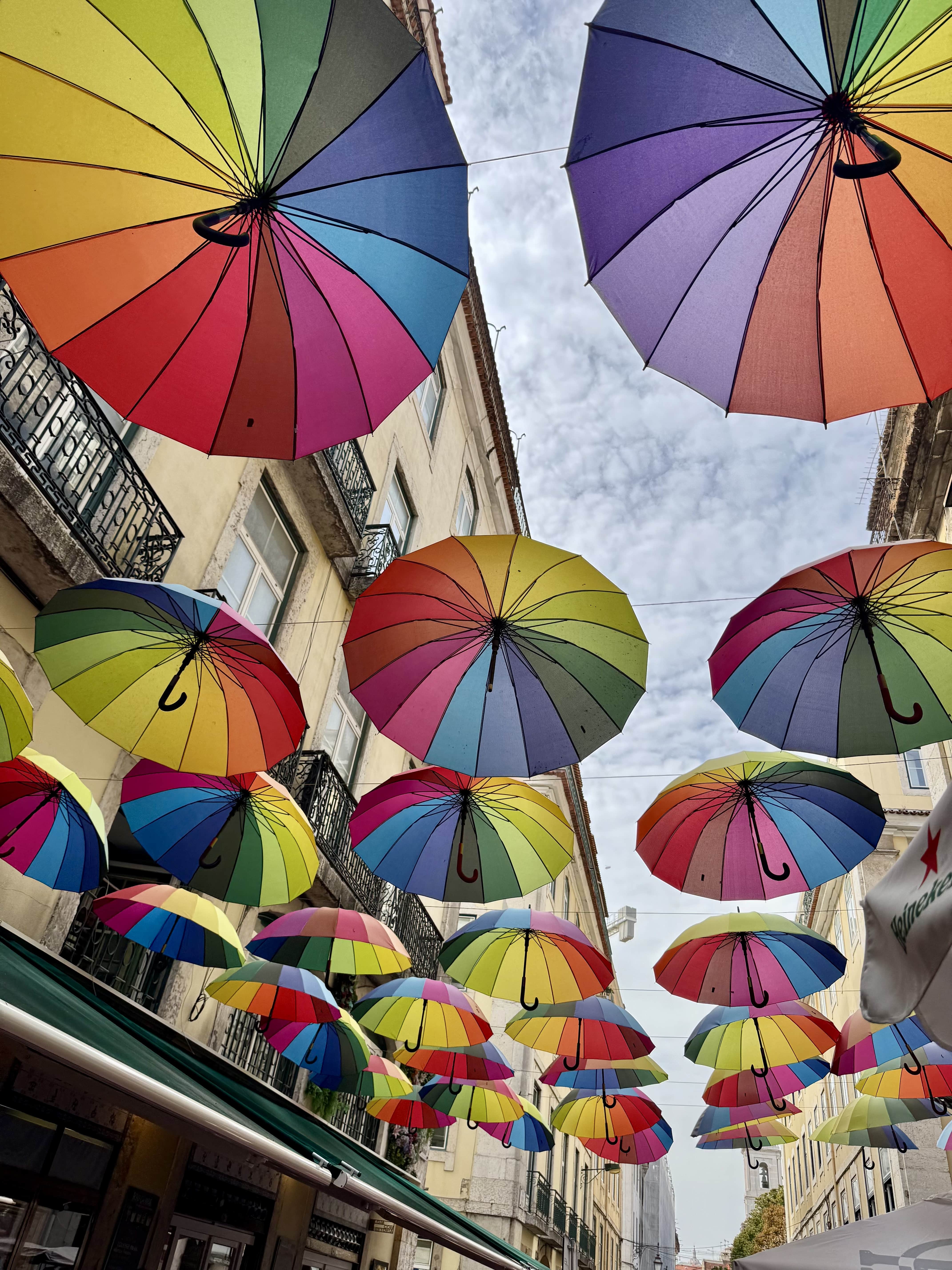 Colorful umbrellas hanging from buildings.