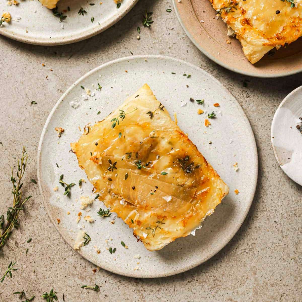 Puff pastry apple tart on a plate garnished with fresh thyme.