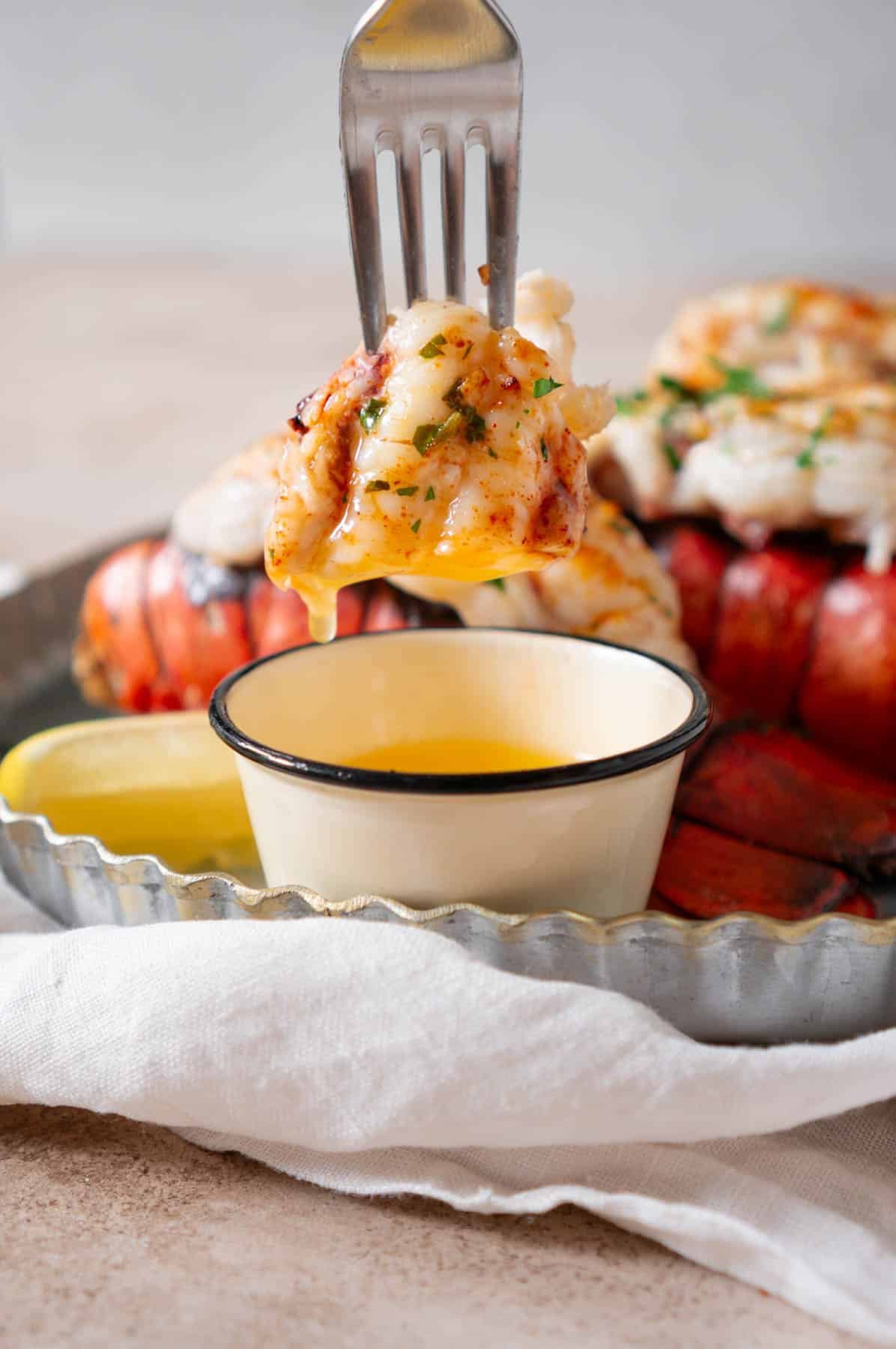 Using a fork to dip lobster meat into melted butter.