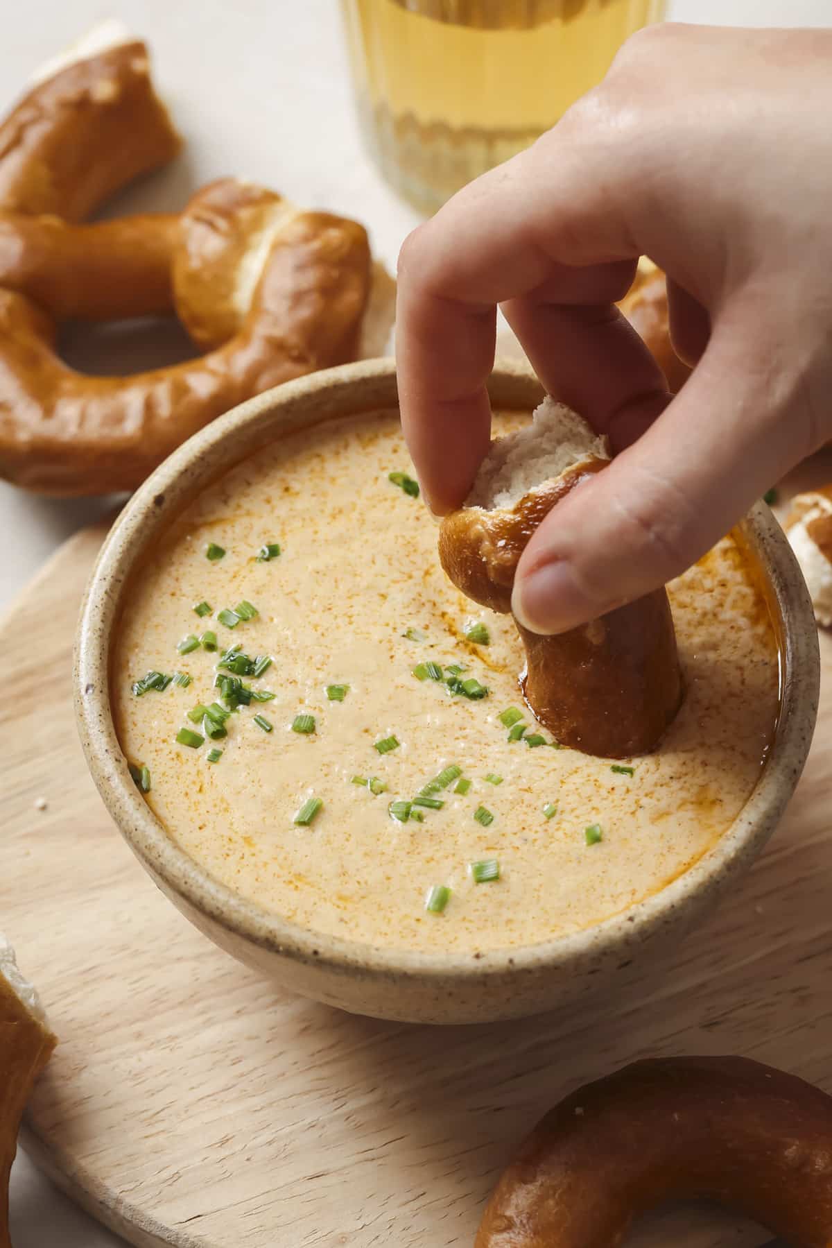 Dipping a pretzel in Crockpot Beer Cheese Dip.