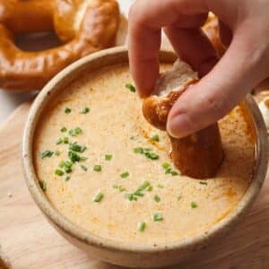Dipping a pretzel in Crockpot Beer Cheese Dip.