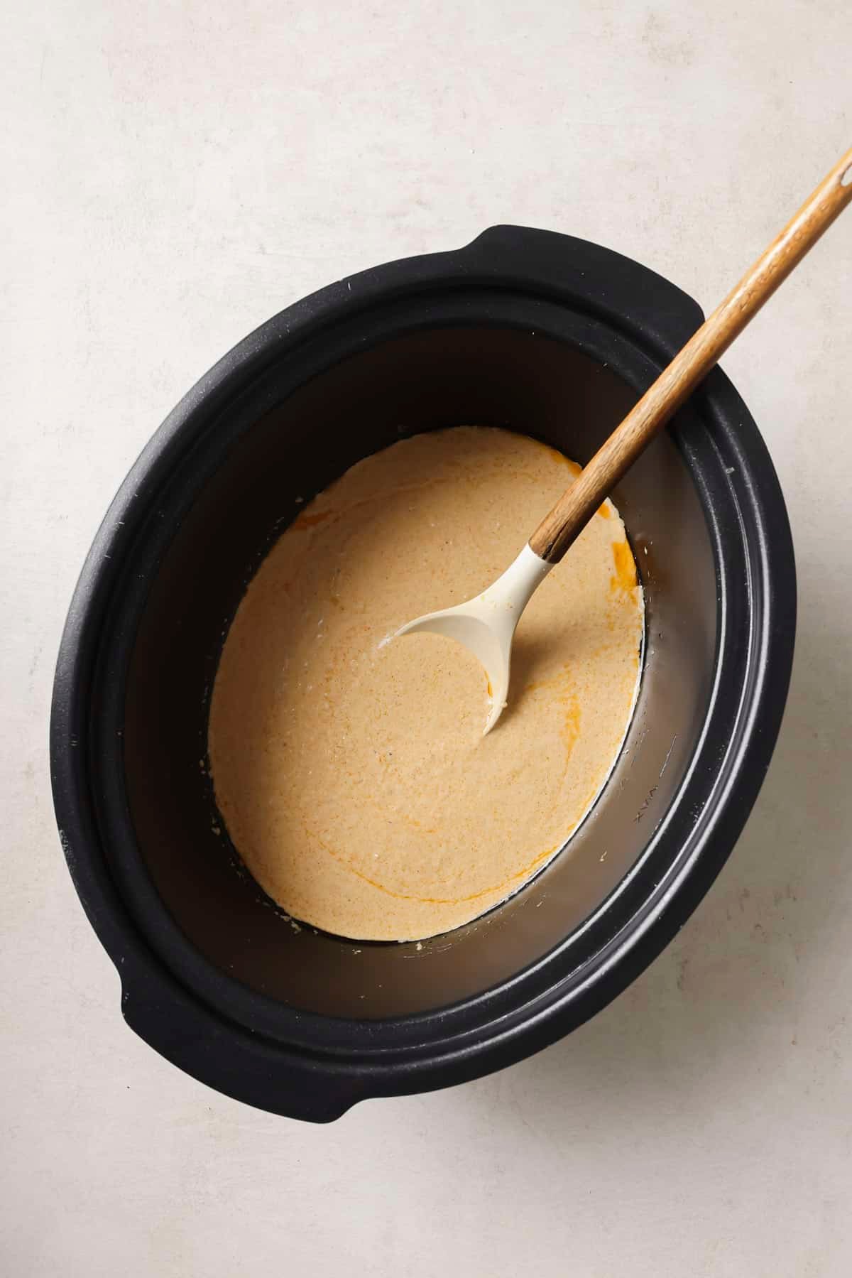 Stirring beer cheese dip in a crockpot until smooth.