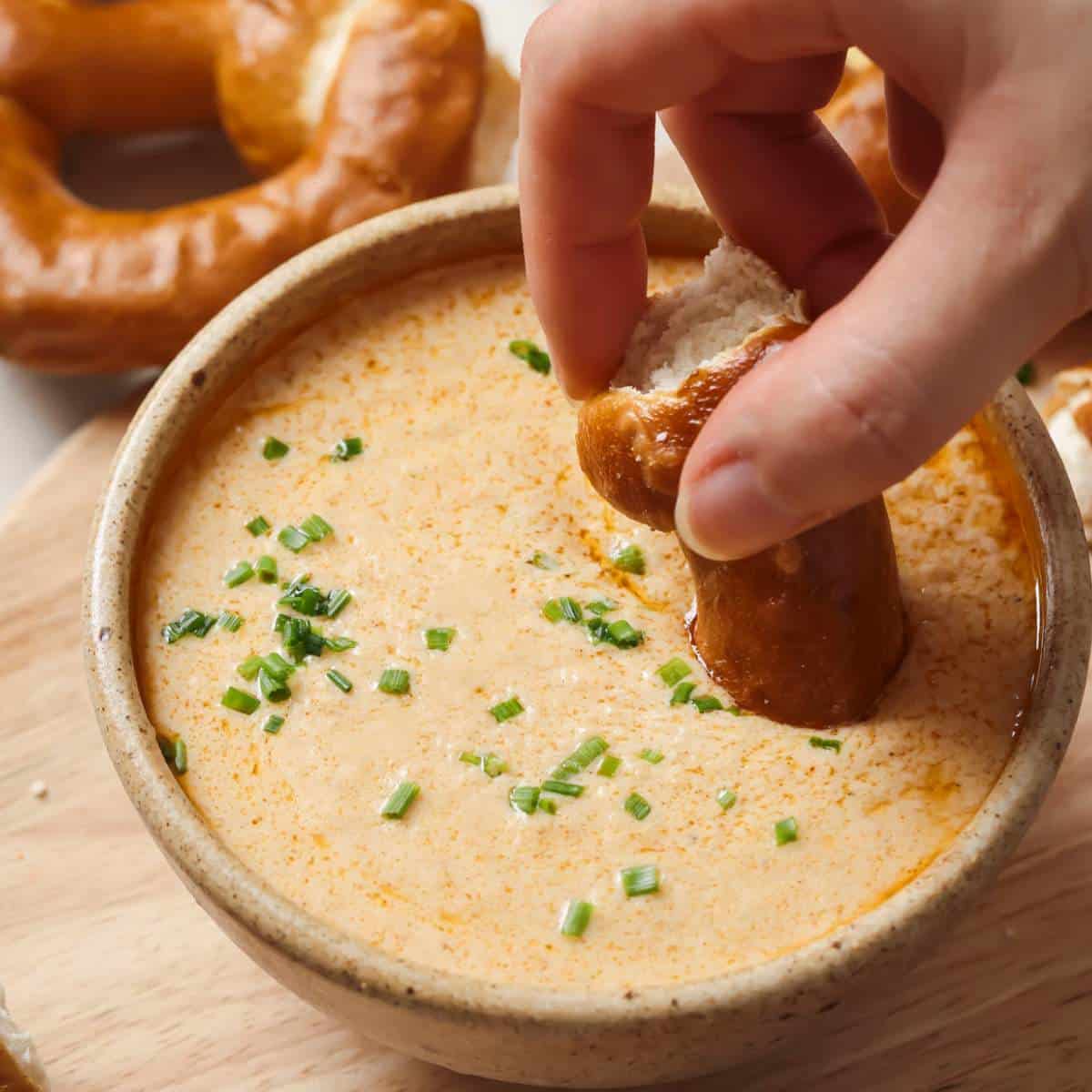Dipping a pretzel in Crockpot Beer Cheese Dip.