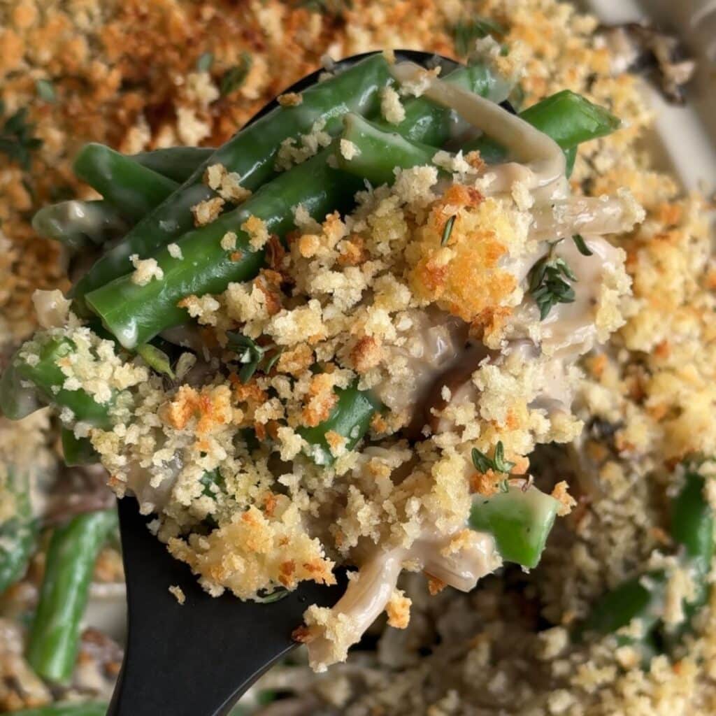 Green bean casserole with crispy panko on a serving spoon.