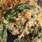 Green bean casserole with crispy panko on a serving spoon.