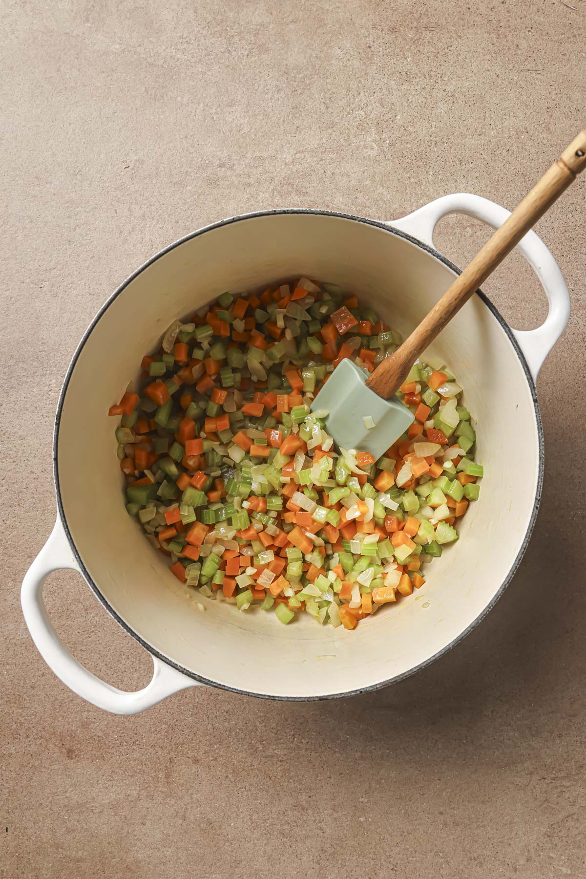 Sautéing vegetables with a spatula in a large pot.