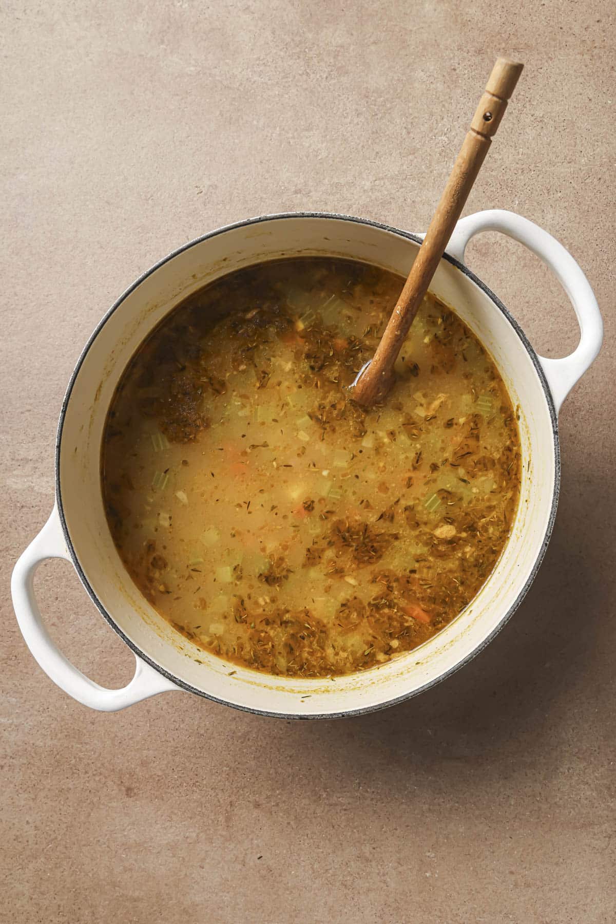 Stirring potatoes with veggies in a broth.