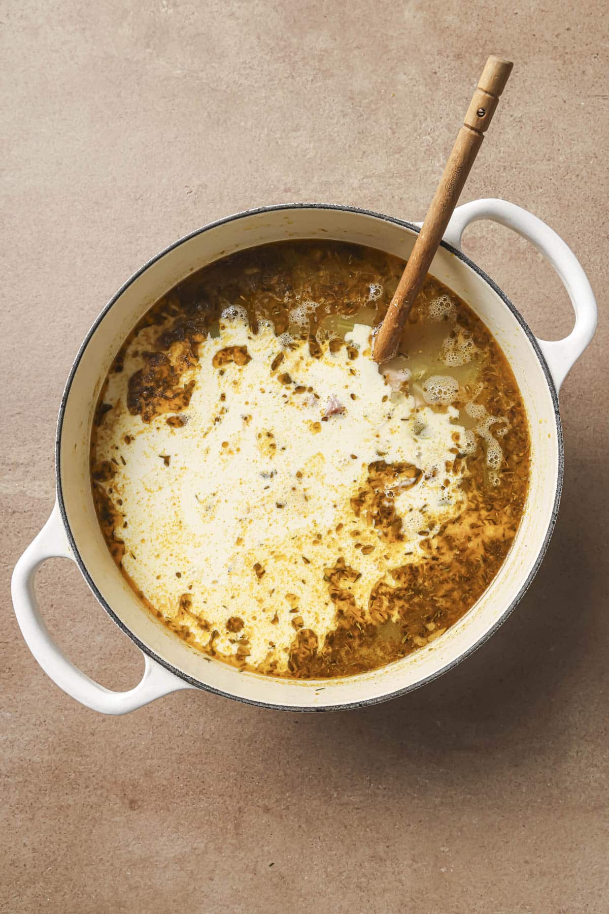 Stirring in cream to soup in a pot.