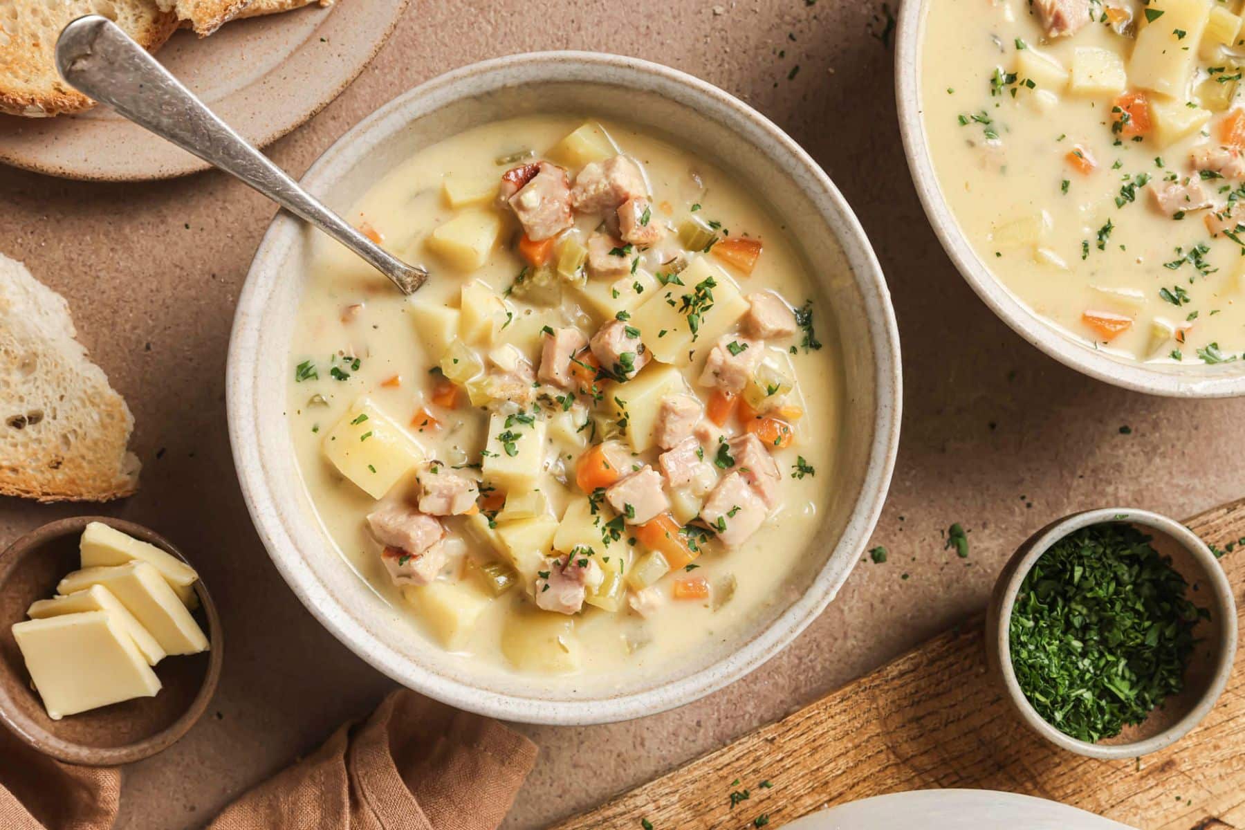 Two bowls filled with ham and potato soup with a spoon in one.