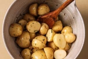 Tossing potatoes in oil and seasonings.