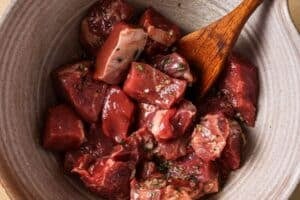 Tossing steak in oil and seasonings.