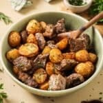 A green bowl full of air fryer steak and potatoes.