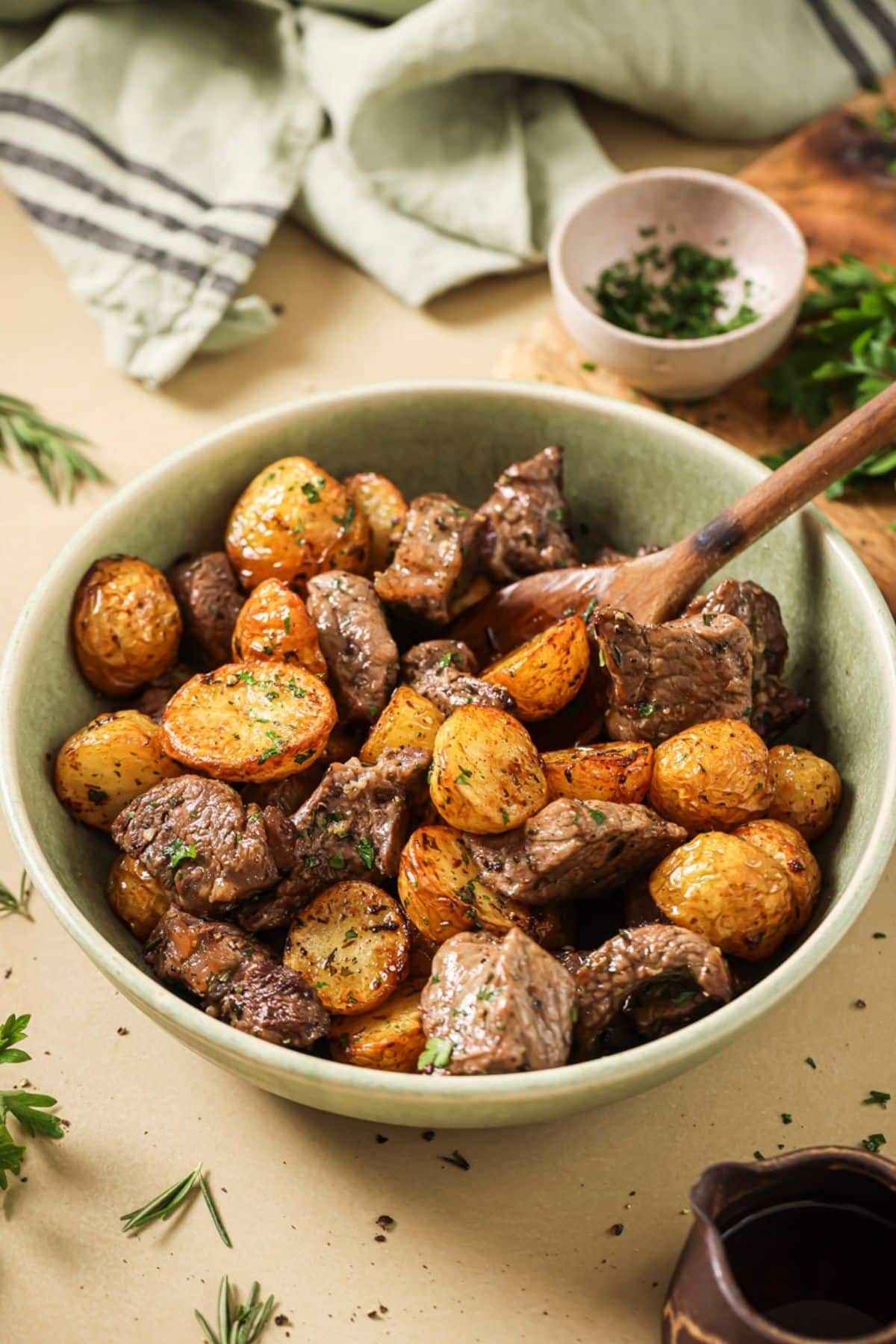 A green bowl with air fryer steak and potatoes.